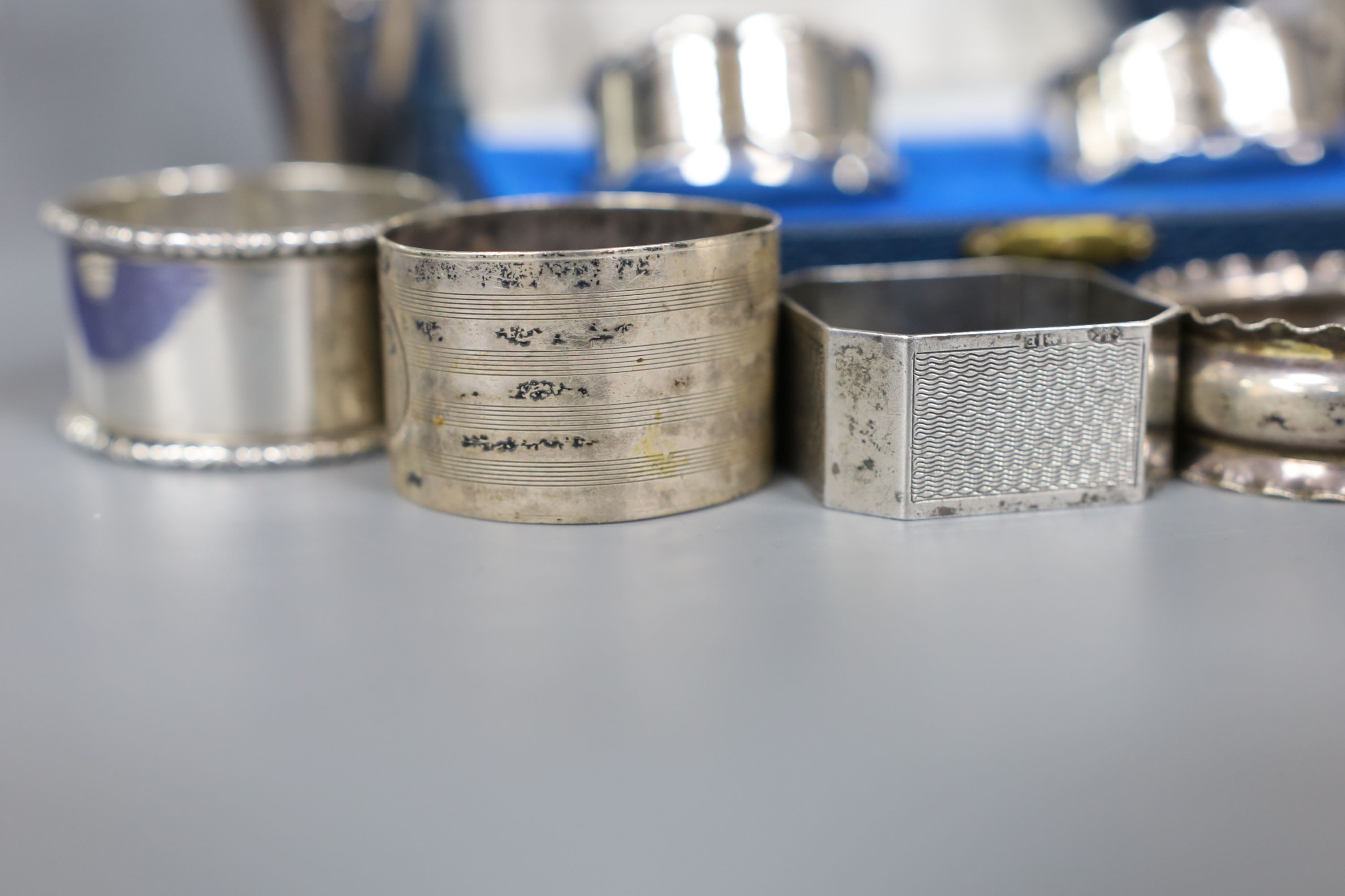 A cased pair of silver napkin rings, five others including one white metal and a two small silver vases, weighted.